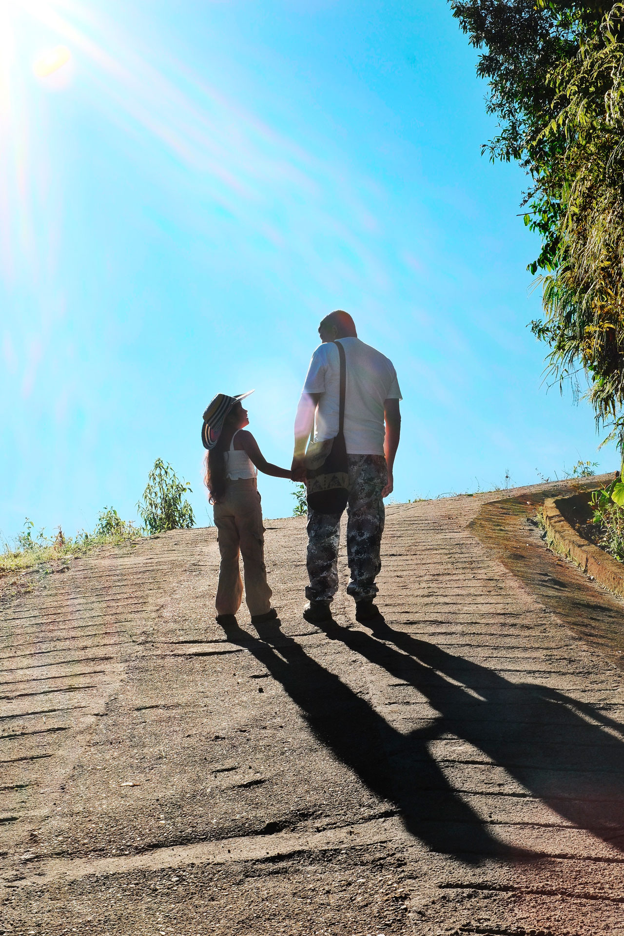 Un padre y su hija caminan de la mano mientras se miran.